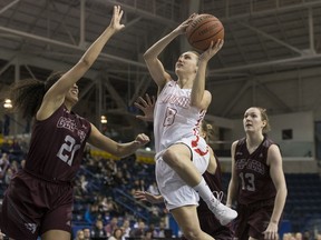 Laval Rouge Claudia Emond, centre, drives to the net as Ottawa Gee-Gees' Brigitte Lefevre-Okankwu, left, attempts to defend during U Sports Canadian women's basketball championship semifinal action in Toronto on Saturday.