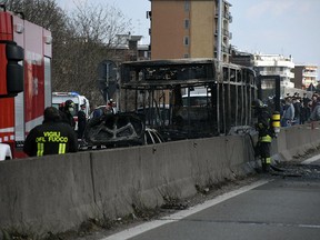 Firefighters stand by the gutted remains of a bus in San Donato Milanese, near Milan, Italy, March 21, 2019. (Daniele Bennati/ANSA via AP)