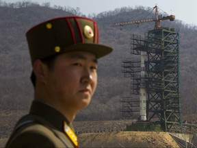 In this April 8, 2012, file photo, a soldier stands in front of the Unha-3 rocket at a launching site in Tongchang-ri, North Korea. (AP Photo/David Guttenfelder, File)