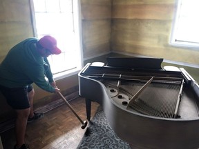 In this Feb. 26, 2019 photo, artist Aaron Angelo takes a sledgehammer to the leg of a baby grand piano in a house where two rooms are being transformed to look as they might have looked once floodwaters receded following Hurricane Katrina in New Orleans.