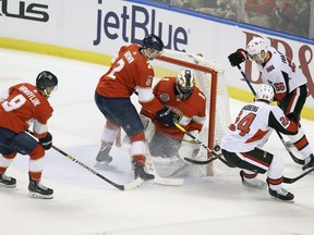 Ottawa Senators' Oscar Lindberg (24) reaches for the puck with Magnus Paajarvi (56) as Florida Panthers goalkeeper Roberto Luongo (1), Jayce Hawryluk (8) and Josh Brown (2) defend during the first period of an NHL hockey game, Sunday, March 3, 2019, in Sunrise, Fla.