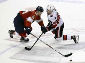 Florida Panthers' Mike Matheson, left, and Ottawa Senators' Mikkel Boedker  battle for the puck during the third period of an NHL hockey game, Sunday,  in Sunrise, Fla.