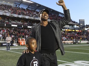 Former Ottawa Redblacks quarterback Henry Burris walks with his son Barron during a ceremony honouring his career in 2017. (THE CANADIAN PRESS)