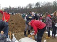 Volunteers gather around the sand pile in the middle of the Constance Bay Community Centre parking lot to sandbag for residents affected by the floods.