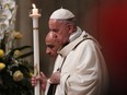 Pope Francis holds an altar candle as he presides over the Easter Vigil at St. Peter's Basilica in the Vatican on Saturday.