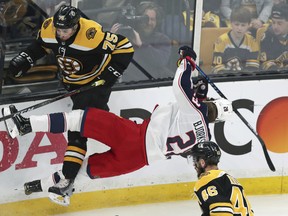 The beatdown continues for Columbus Blue Jackets forward Oliver Bjorkstrand (right) as he is upended by Boston Bruins defenceman Connor Clifton while chasing the puck last night at the TD Garden.