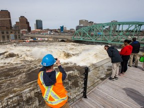 From the safety of the Zibi viewing platform visitors take photos of the enormous amounts of water flowing over the Chaudière Falls and under the closed Chaudière Bridge.