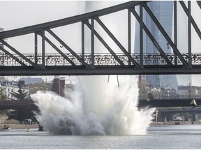 A large water fountain rises behind the Iron Bridge when a 250 kilogram US-American bomb from the Second World War in the Main River is detonated with a blast in Frankfurt, Germany, Sunday, April 14, 2019.  About 600 people had to leave their homes for security reasons. On the right in the background you can see the headquarters of the European Central Bank (ECB). (Frank Rumpenhorst/dpa via AP) ORG XMIT: PRO101