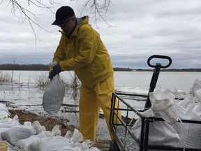 Dave McKay sandbags behind his cottage on Moorhead Driver near Fitzroy Harbour on Saturday.