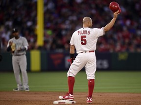 The Los Angeles Angels' Albert Pujols tips his helmet to fans after hitting an RBI double as Seattle Mariners shortstop Tim Beckham claps during the third inning of a baseball game Saturday, April 20, 2019, in Anaheim, Calif. With that RBI, Pujols tied Babe Ruth for fifth place on the all-time RBI list with 1,992.