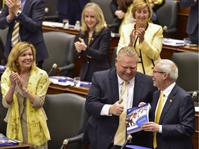 Ontario Finance Minister Vic Fedeli is applauded by Premier Doug Ford and other MPPs after presenting the 2019 budget at the legislature in Toronto on Thursday, April 11, 2019.