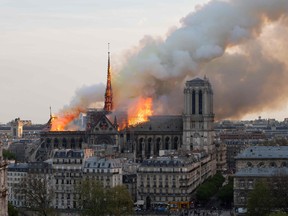 Smoke billows as flames burn through the roof of the Notre-Dame de Paris Cathedral on April 15, 2019, in the French capital Paris. - A huge fire swept through the roof of the famed Notre-Dame Cathedral in central Paris on April 15, 2019, sending flames and huge clouds of grey smoke billowing into the sky.