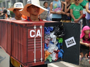 Filipino environmental activists wear a mock container filled with garbage to symbolize the 50 containers of waste that were shipped from Canada to the Philippines, as they hold a protest outside the Canadian embassy at Makati, Philippines on May 7, 2015. (THE CANADIAN PRESS/AP, Aaron Favila)