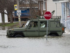 A military jeep moves through floodwaters on a closed street in Gatineau, Que., Tuesday, April 23, 2019.