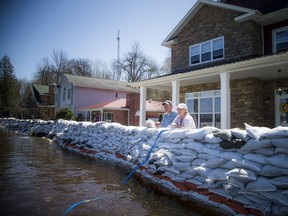 Rhoddy's Bay was hit with very high flood waters from the Ottawa River over the past few weeks, causing damage to homes and cottages in the area. Angie and Doug MacCrae stand beside their three foot thick sand-wall in front of their Rhoddy's Bay home Sunday.