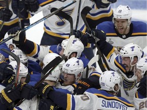 St. Louis Blues teammates mob Carl Gunnarsson, who scored the winning goal against the Boston Bruins during the first overtime period in Game 2 of the NHL hockey Stanley Cup Final, on Wednesday in Boston.