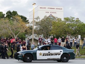 In this Feb. 28, 2018 file photo, a police car drives near Marjory Stoneman Douglas High School in Parkland, Fla., as students return to class for the first time since a former student opened fire there with an assault weapon. Republican Florida Gov. Ron DeSantis has signed a bill that will allow more classroom teachers to carry guns in school, a response to last year's mass shooting at a Parkland high school.