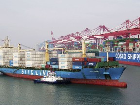 In this Wednesday, May 8, 2019, photo, a barge pushes a container ship to the dockyard in Qingdao in eastern China's Shandong province.