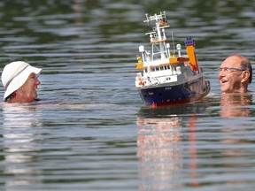 An elderly couple swim past a model boat.