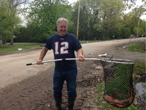 Tony Menchini holds one of three carp that have been swimming around his lawn. Luke Carroll/Postmedia