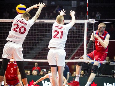 Serbia's Milan Katic powers the ball through a block by Canada's Arthur Szwarc and Brett James Walsh.