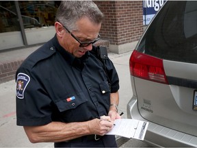 Parking Control Officer Danny Lafrance writes a ticket for a vehicle parked in a no-stopping zone on Slater Street near Bank Street.