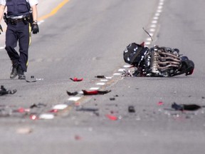 A police officer surveys the scene of a deadly motorcycle wreck