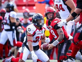 Calgary Stampeders quarterback Bo Levi Mitchell is upended by Kevin Brown the Ottawa Redblacks.