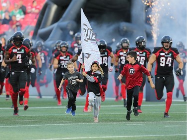 Youngsters lead the Redblacks onto the field at the start of the game as the Ottawa Redblacks take on the Saskatchewan Roughriders in CFL action at TD Place in Ottawa. Photo by Wayne Cuddington / Postmedia