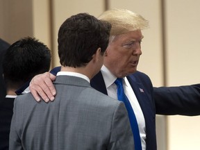 United States President Donald Trump puts his hand on Canadian Prime Minister Justin Trudeau's shoulder as they talk before the start of a plenary session at the G20 Summit in Osaka, Japan, Saturday June 29, 2019.
