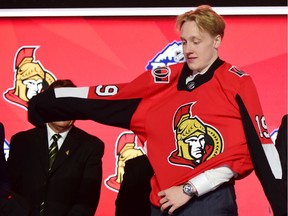 Lassi Thomson puts on a Senators jersey after being selected at No. 19 in the NHL draft on Friday night in Vancouver.