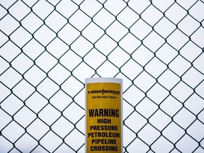 A sign warning of an underground petroleum pipeline is seen on a fence at Kinder Morgan's facility where work is being conducted in preparation for the expansion of the Trans Mountain Pipeline, in Burnaby, B.C., on Monday April 9, 2018.