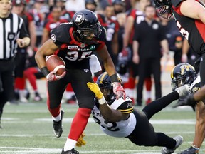 Redblacks running back John Crockett is grabbed Hamilton Tiger-Cats’ Justin Tuggle during Saturday night’s game. (THE CANADIAN PRESS)