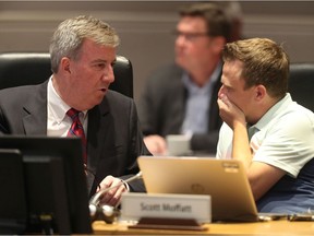 Ottawa mayor Jim Watson confers with Coun. Scott Moffatt during council at city hall on Wednesday.