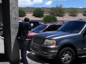 A police officer in Phoenix, Arizona points their gun at unarmed parents of a child that shoplifted. (Screenshot/Twitter)