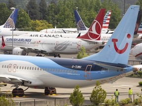 Workers stand near Boeing 737 MAX airplanes as they sit parked at a Boeing facility adjacent to King County International Airport, known as Boeing Field, on May 31, 2019 in Seattle, Wash.