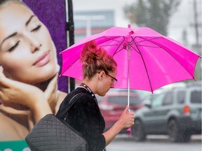A woman with an umbrella walks past a billboard.