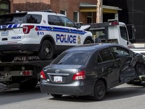 Tow trucks remove vehicles following a collision between an Ottawa Police Service SUV and a compact car near the intersection of Bank Street and Cooper Street on Friday.