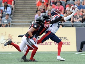 Ottawa Redblacks defensive backs Antoine Pruneau (left) and Corey Tindal Sr. chase Montreal Alouettes wide receiver B.J. Cunningham as he attempts to pull in a pass during first quarter CFL action on Saturday.