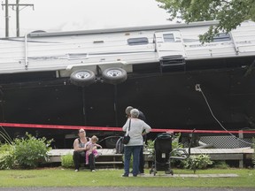 People are shown next to an overturned trailer home following a storm at a campground in Saint-Roch-de-l'Achigan, Que. near Montreal, Friday, July 12, 2019.