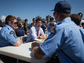 Prime Minister Justin Trudeau, back centre, talks with members of the Canadian Coast Guard after an announcement at the Kitsilano Coast Guard Base, in Vancouver, on Monday July 29, 2019.