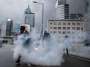 A protester runs amid tear gas during clashes with police outside the Central Government Complex after an anti-government rally on Saturday in Hong Kong.