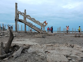 People walk and take pictures at the ruins of a Buddhist temple which has resurfaced in a dried-up dam due to drought, in Lopburi, Thailand August 1, 2019. REUTERS/Soe Zeya Tun