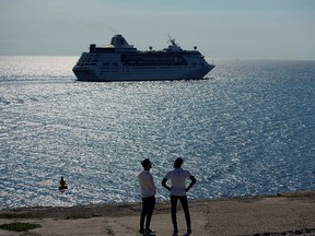 Men watch the cruise ship MS Empress of the Seas, operated by Royal Caribbean International, as it leaves the bay of Havana, Cuba, June 5, 2019. (REUTERS/Alexandre Meneghini/File Photo)
