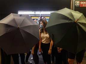 Protesters use umbrella to shield themselves during a protest to prevent commuters from reaching work in business districts at Lai King MTR station in Hong Kong on August 5, 2019. - Pro-democracy protesters caused chaos on Hong Kong's subway system as they kicked off an attempted city-wide strike to ramp up pressure on the financial hub's embattled pro-Beijing leaders after weeks of protests.
