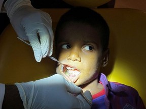A doctor examines the teeth of a 7-year-old boy inside a hospital in Chennai, India, August 2, 2019.