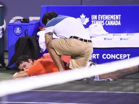 Milos Raonic receives medical attention on the court during his match against Felix Auger-Aliassime at the Rogers Cup at IGA Stadium in Montreal on Aug. 7, 2019.