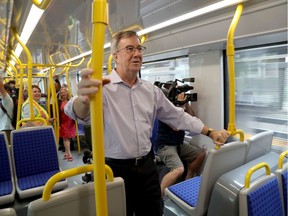 Mayor Jim Watson hangs on as the media and local politicians are taken on an LRT ride in Ottawa on Friday, Aug. 23, 2019.