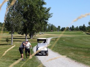 Vinny Sacca hits from the rough on the ninth hole during the Ottawa Sun Scramble at DragonFly on Tuesday as partner Bobby Paquette looks on. JEAN LEVAC/POSTMEDIA