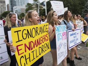 In July 2018, protesters in Toronto hold up signs at a rally in support of keeping the 2015 sex ed curriculum in Ontario schools.